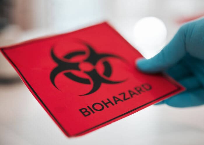 person wearing gloves holding a biohazard sign